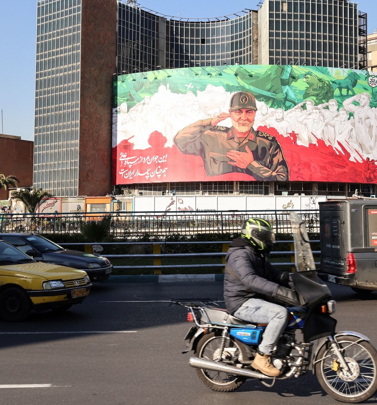 Iranians ride their motorbike past a huge banner of former Iran Islamic Revolutionary Guard Corps (IRGC) Quds Force commander Qasem Soleimani ahead of the sixth anniversary of his assassination, in Tehran, Dec. 31, 2025. 
