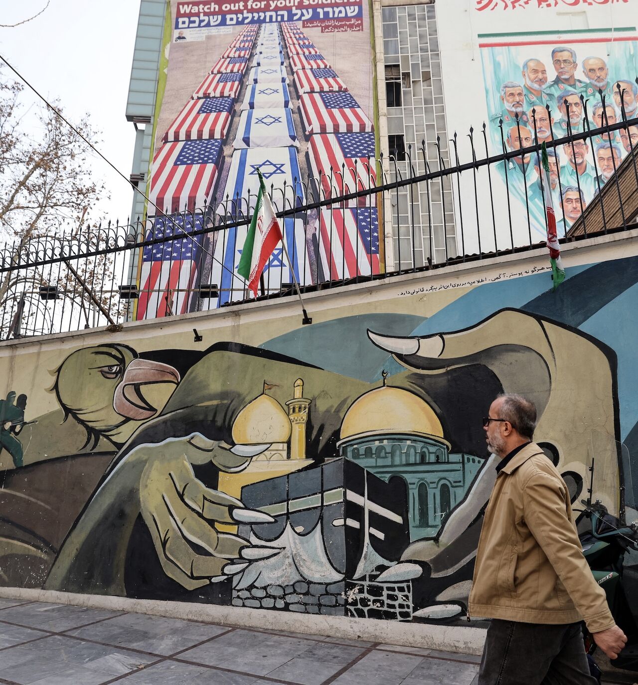 An Iranian man walks past an anti-US and anti-Israel banner hanging on a building in Palestine Square in Tehran on Jan. 27, 2026.