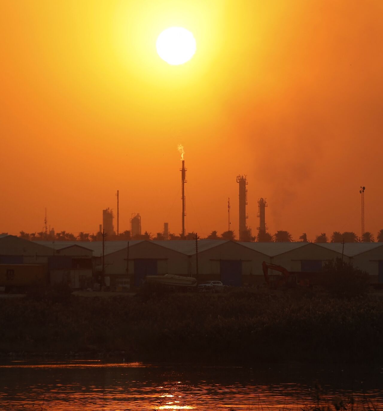 The sun sets behind burning gas flares at the Dora Oil Refinery Complex in Baghdad on Nov. 24, 2025. 