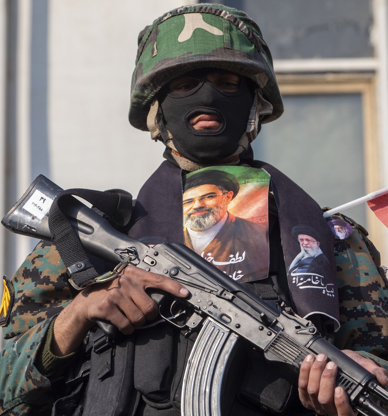 A security forces member with a picture of Iran's new supreme leader, Ayatollah Mojtaba Khamenei, watches over demonstrators as they gather for a rally in support of the new supreme leader at Enghelab Square on March 9, 2026 in Tehran, Iran. 