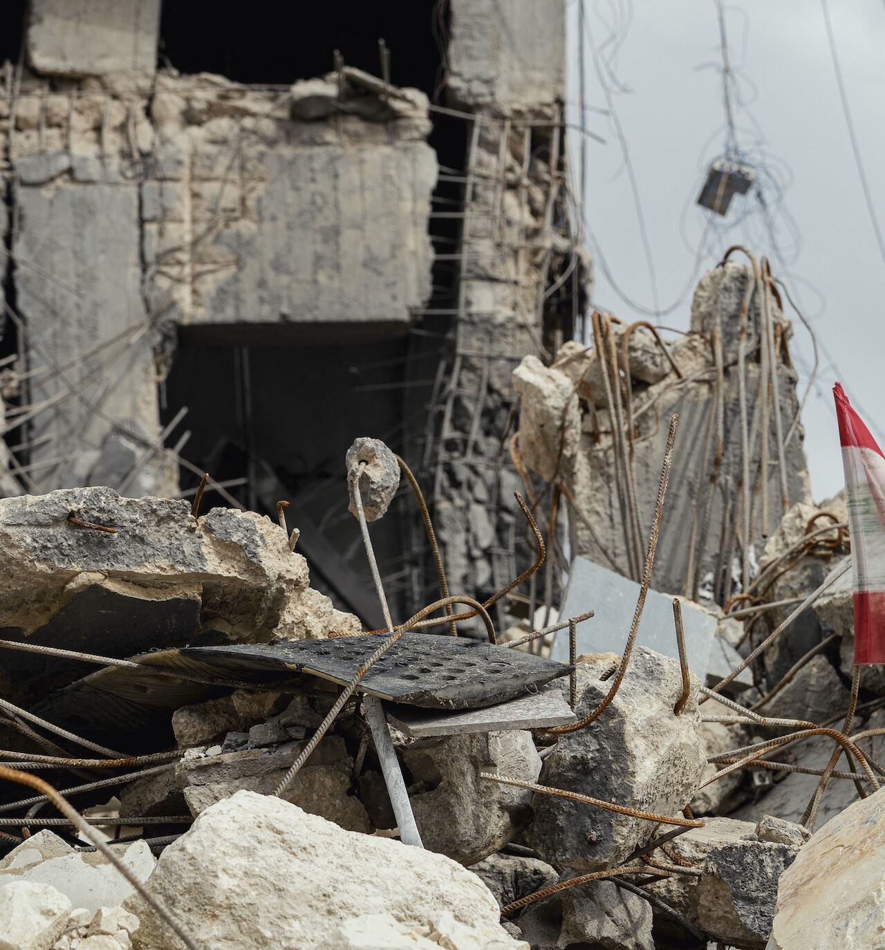 A view shows a Lebanese flag positioned among shattered concrete and twisted rebar, remnants of a destroyed building, in Sidon, Lebanon, on May 3, 2026. 