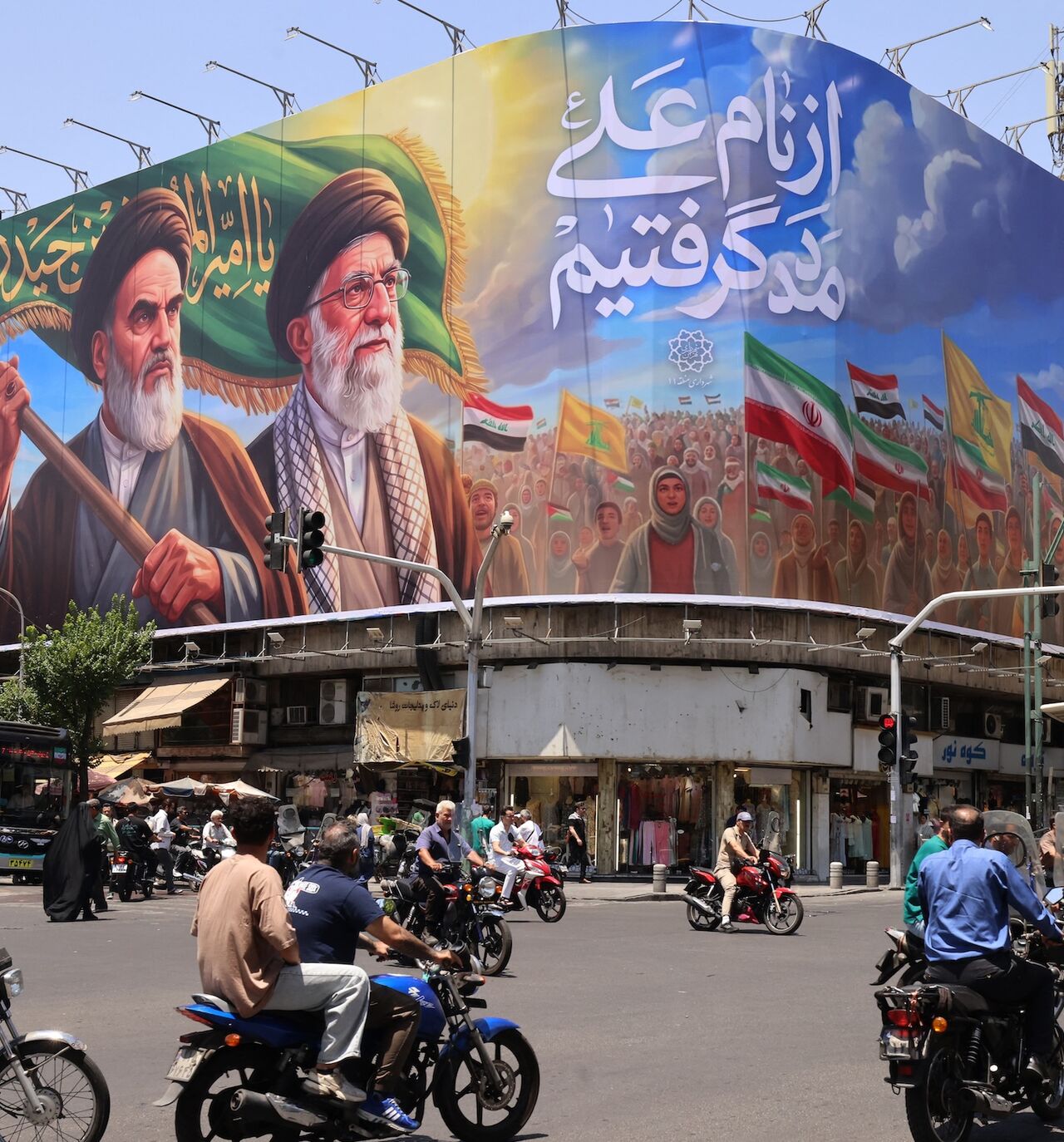 People ride motorcycles past a large billboard showing portraits of Iran's late supreme leader, Ayatollah Ruhollah Khomeini (L), and slain supreme leader Ayatollah Ali Khamenei (R) in central Tehran on June 8, 2026. 