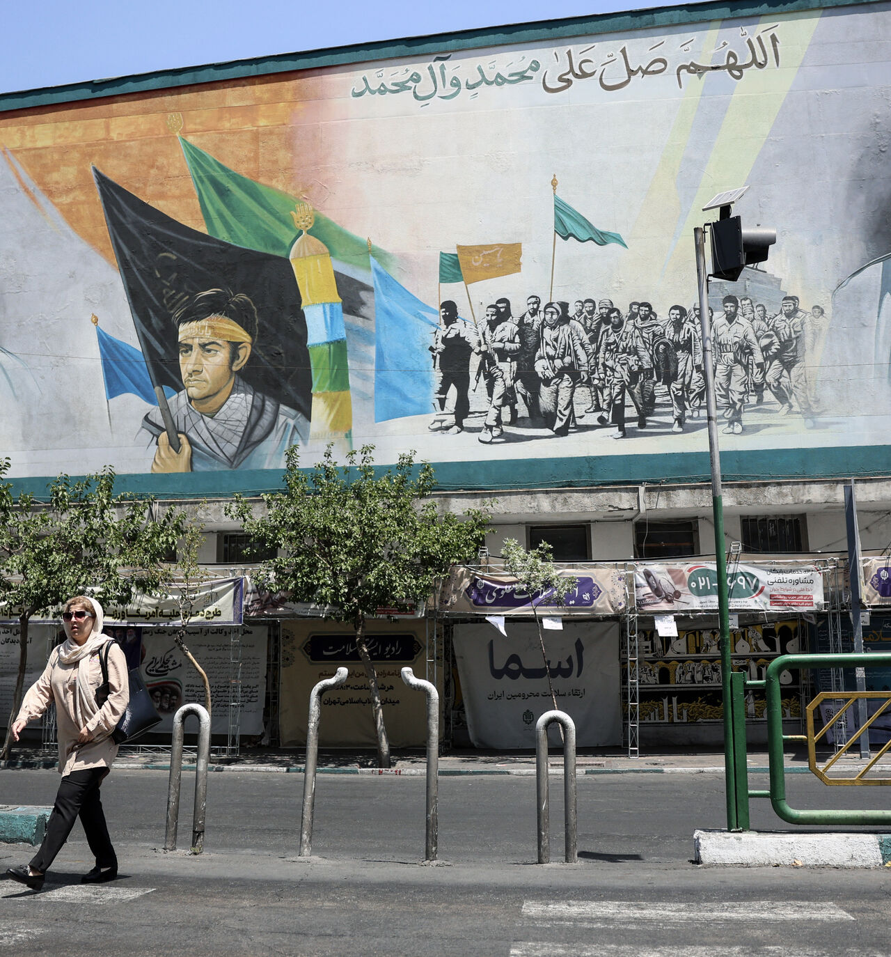 An Iranian woman walks past a mural depicting late Iranian supreme leaders Ayatollah Ali Khamenei (L) and Ayatollah Ruhollah Khomeini (R) in Tehran on June 18, 2026. 