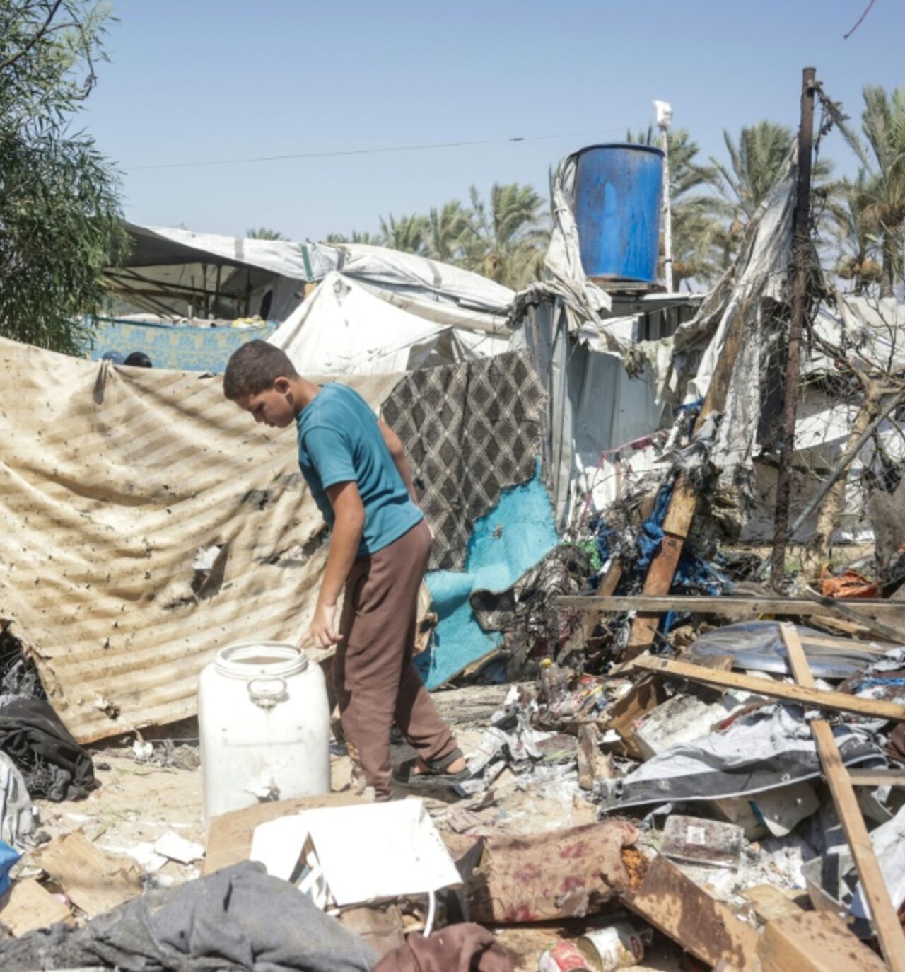 A displaced Palestinian youth inspects the damage of an alleged Israeli strike on a tent in Khan Yunis, in the southern Gaza Strip
