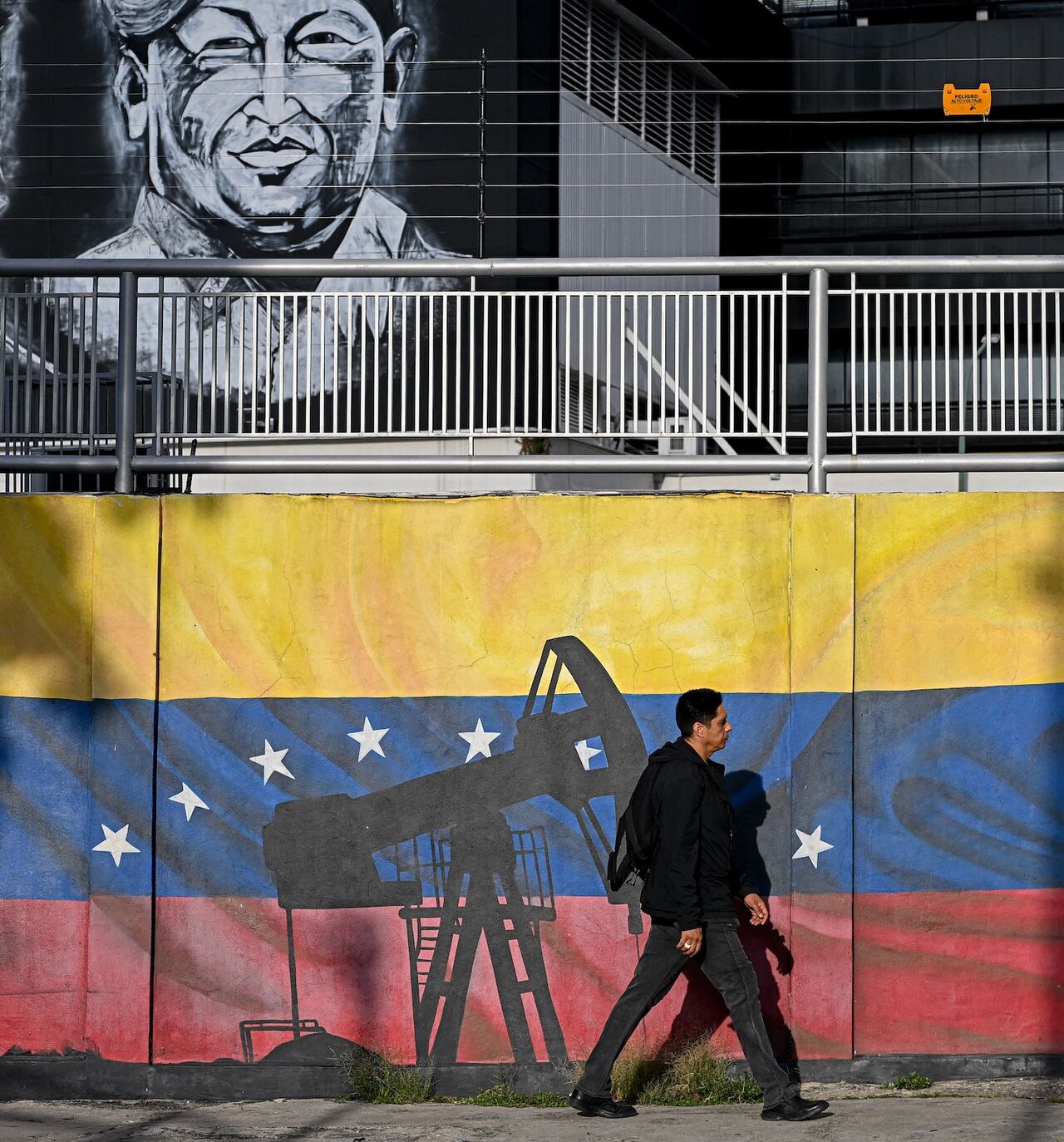 A man walks past a mural depicting oil pumps and the Venezuelan flag, with portraits of Venezuelan independence leader Simon Bolivar (L) and former late President Hugo Chavez (R), in Caracas, Venezuela, on Sept. 3, 2026.
