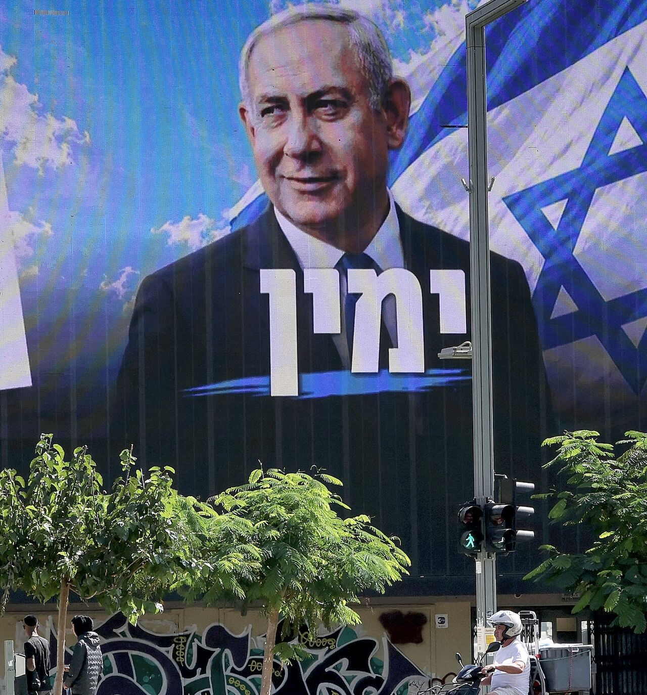 A man on a scooter rides past a billboard featuring Israel's Prime Minister Benjamin Netanyahu of the Likud party, in Tel Aviv, on Oct. 20, 2026. 