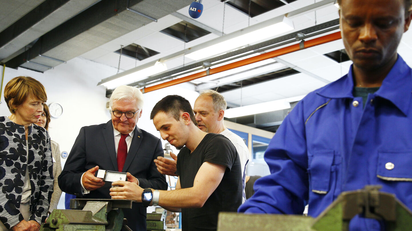 German President Frank-Walter Steinmeier and First Lady Elke Buedenbender Chat with refugees attending the training program for mechanics while visiting the Gallinchen job training and technology center on June 23, 2017 in Cottbus, Germany