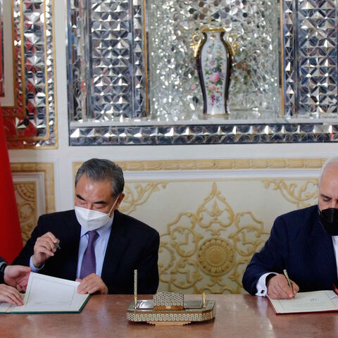 Iranian Foreign Minister Mohammad Javad Zarif (R) and his Chinese counterpart Wang Yi (C), sign an agreement in the capital Tehran, on March 27, 2021.