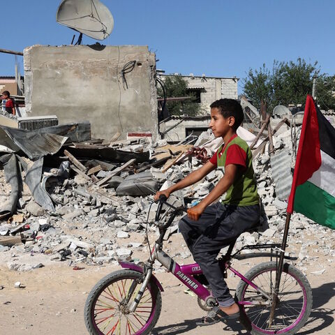 A Palestinian child rides his bicycle in front of the ruins of a building destroyed during recent Israeli bombing in Rafah, in the southern Gaza Strip, on May 26, 2021.