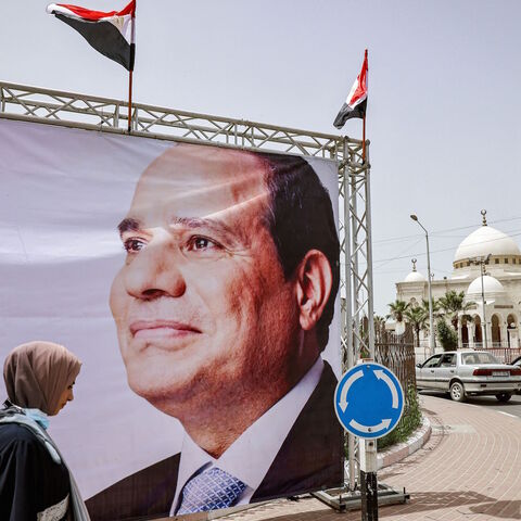 Women walk past a giant banner depicting Egypt's President Abdel Fattah al-Sisi amidst preparations to receive a visiting Egyptian intelligence delegation in Gaza City on May 31, 2021. 