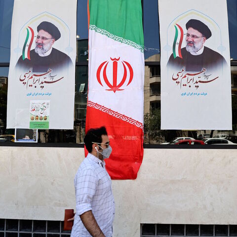 An Iranian man walks by posters of presidential candidate Ebrahim Raisi outside a campaign office in Tehran on June 7, 2021. 