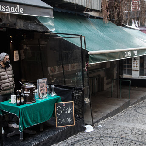 Faruk Ugur waits for customers while selling hot wine at the entrance to his closed restaurant in the Kadikoy district on February 23, 2021 in Istanbul, Turkey.