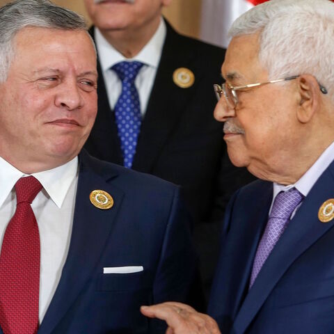 Jordan's King Abdullah II speaks with Palestinian president Mahmoud Abbas while standing for the group family photo with other Arab leaders during the 30th Arab League summit in the Tunisian capital Tunis on March 31, 2019. 