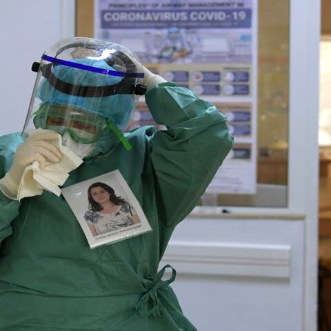 Amira Jamoussi, with a picture of herself pinned on her protective outfit to help others recognize her, gets ready to see patients at the Abderrahmane Memmi Hospital.