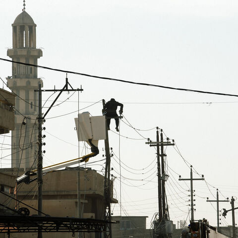 An Iraqi municipal worker fixes the cables of an overhead power line in al-Zahraa neighborhood in Mosul, during an ongoing military operation against the Islamic State, Iraq, Jan. 11, 2017.
