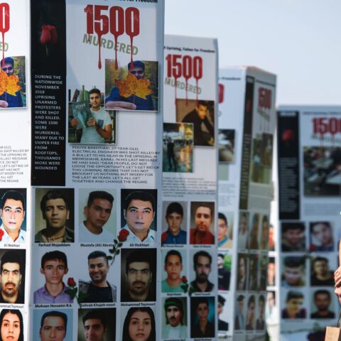 A man walks past some of the thousands of photos of people killed in Iran during the 1988 massacre of political prisoners.