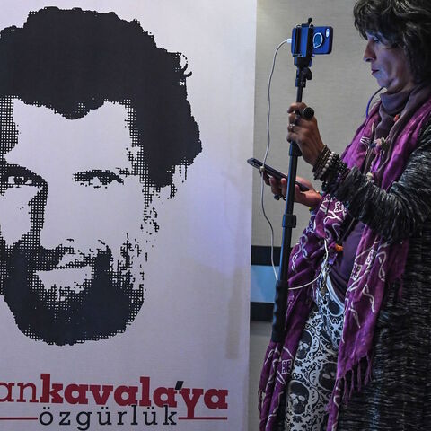 A journalist stands in front of a poster featuring jailed businessman and philanthropist Osman Kavala during a press conference of his lawyers on Oct. 31, 2018.  