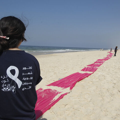 A Palestinian girl stands on a beach near a pink ribbon as part of the Breast Cancer Awareness campaign, Gaza City, Gaza Strip, Oct. 10, 2012.