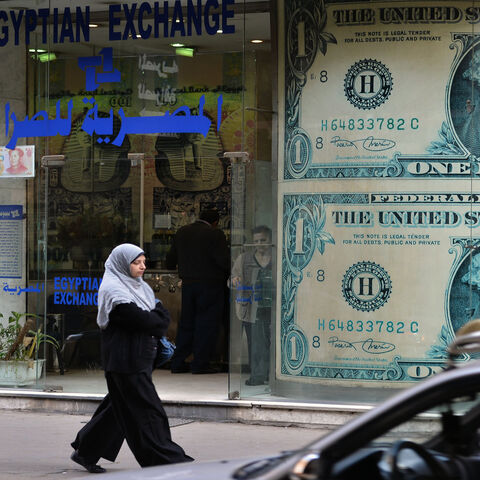 A woman walks past an exchange store, Cairo, Egypt, Jan. 6, 2013.