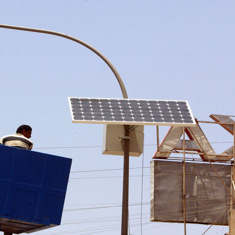 A municipal worker is lowered after adjusting a solar panel attached to the top of an electricity pylon along the central isle of a main road in Karada district, Baghdad, Iraq, May 24 2008.