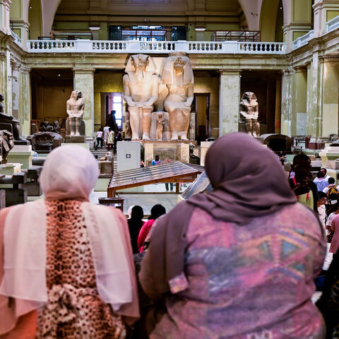A group of women sit in front of the Colossal statue of Amenhotep III and Tiye at the Cairo Museum, Cairo, Egypt, July 15, 2019.