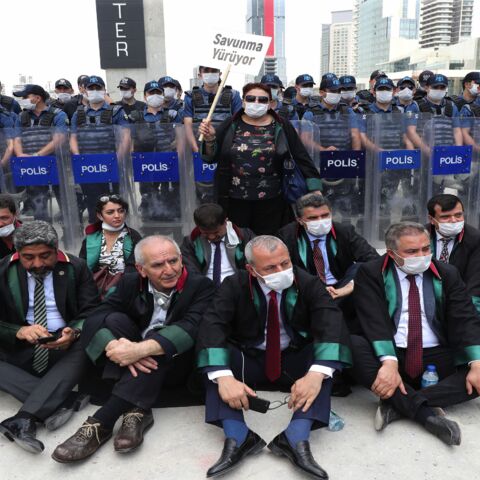 Senior lawyers protesting against a draft bill governing the organization of bar associations sit on the ground during a rally in front of Turkish riot policemen, in Ankara on June 22, 2020.