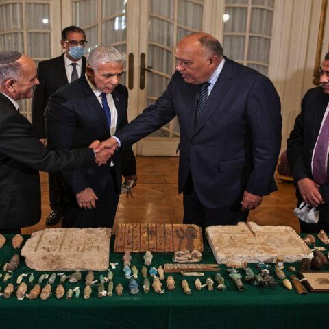 Egypt's Foreign Minister Sameh Shoukry (C) shakes hands with the director of the Israel Antiquities, Authority Eli Escozido (L).