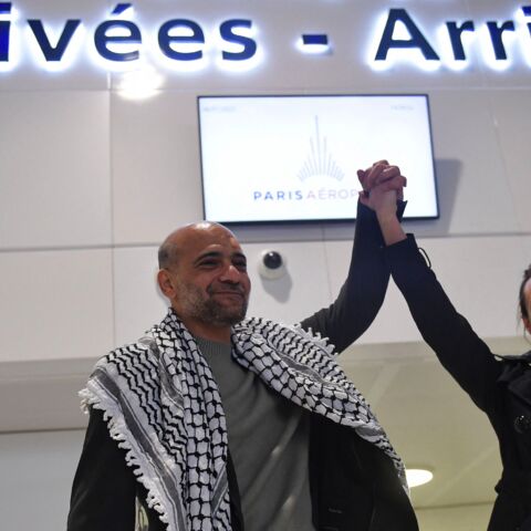 Egyptian-Palestinian political activist Ramy Shaath holds up the arm of his wife, Celine Lebrun-Shaath, as he arrives at Roissy Airport in Roissy, outside Paris, on Jan. 8, 2022.