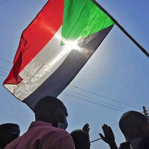 Sudanese protesters raise a national flag as they rally against the October 2021 military coup, in Khartoum on Jan. 13, 2022.