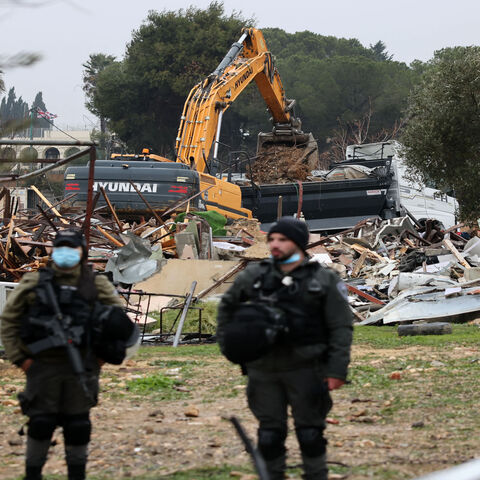 Israeli forces stand guard as machinery clean the ruins of the Palestinian Salhiya family's house, in the Sheikh Jarrah neighborhood, Jerusalem, Jan. 19, 2022.