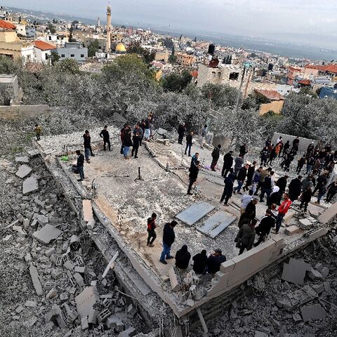 Palestinians gather on the ruins of a Palestinian house demolished by Israeli forces, in the village of Silat al-Harithiya near the flashpoint town of Jenin in the occupied West Bank, on March 8, 2022