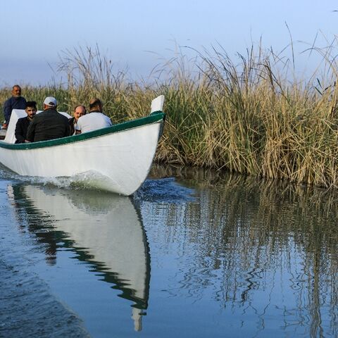 Veterinarian Karrar Ibrahim Hindi (L) sits in an ambulance boat as he heads to treat sick buffaloes, in the marshes of southern Iraq