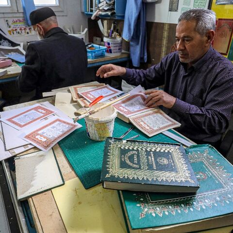 A man assembles pages together to be glued into a volume at a workshop for restoring copies of the Holy Koran, Islam's holy book -- an increasingly popular practice as the price of new Korans goes up in Libya