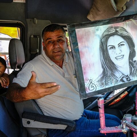 A van driver holds a portrait of Palestinian-American Al Jazeera journalist Shireen Abu Akleh as he passes the spot where she was killed while covering clashes in Jenin in the occupied West Bank