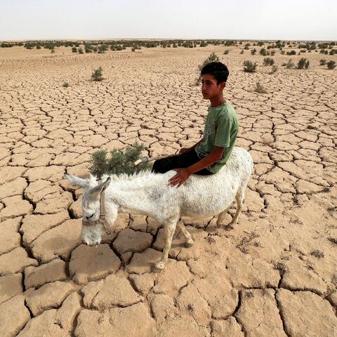 An Iraqi rides a donkey across the dried out lake bed that is all that is left of Lake Hamrin, in normal years a key irrigation reservoir