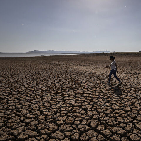 A woman walks over cracked earth at al-Massira dam in Ouled Essi Masseoud village, some 140 kilometres (85 miles) south from Morocco's economic capital Casablanca, on August 8, 2022 amidst the country's worst drought in at least four decades. - Residents of Morocco's Ouled Essi Masseoud village are suffering from a series of successive droughts, prompting them to rely solely on sporadic supplies in public fountains and from private wells. The situation is critical, given the village's position in the agricu