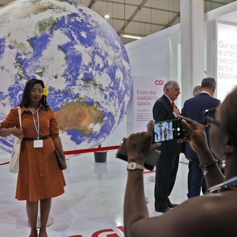 A woman poses for a picture in front of a globe on November 10, 2022, inside the venue hosting the COP27 climate conference, at the Sharm el-Sheikh International Convention Centre, in Egypt's Red Sea resort city of the same name. (Photo by AHMAD GHARABLI / AFP) (Photo by AHMAD GHARABLI/AFP via Getty Images)
