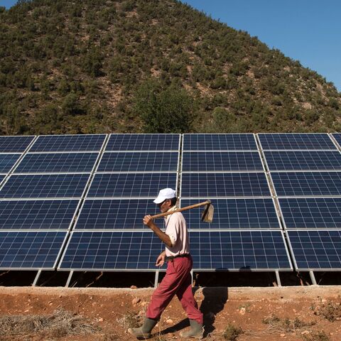 A Moroccan farmer walks past solar panels that are connected to a generator which feeds a pump extracting water from underground in Tafoughalt, a little village deep in the mountains of Morocco's eastern Berkane province, on October 31, 2016. As the Cop22 gets underway in Marrakesh, negotiators are thrashing out the details of a landmark global agreement designed to stave off disastrous climate change, but in Tafoughalt that impact is being felt already. Rising temperatures are among the factors making the 