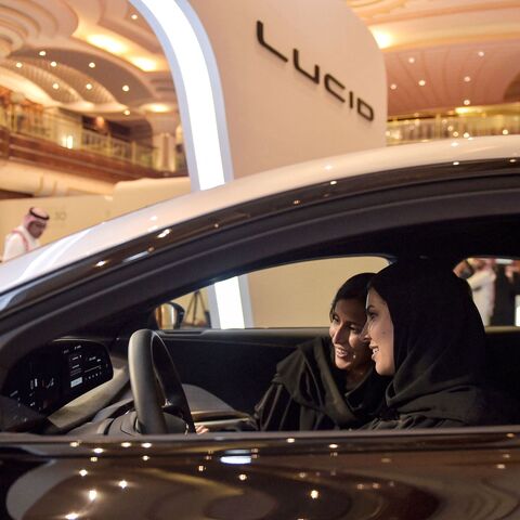 A picture taken on July 14, 2022, ahead of a visit by the United States' president to Saudi Arabia, shows hostesses in a car manufactured by US electric vehicle maker Lucid Group at the KSA Green Transition Journey exhibition in the Red Sea port of Jeddah. - A exhibiton offered a presentation on the Saudi Green Initiative, which also includes goals for tree-planting and reducing emissions. (Photo by Amer HILABI / AFP) (Photo by AMER HILABI/AFP via Getty Images)