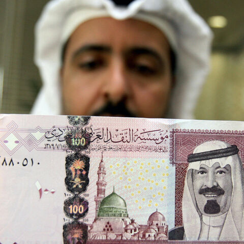 Riyadh, SAUDI ARABIA: A Saudi banker displays the new one hundred riyal banknote bearing the portrait of Saudi King Abdullah bin Abdul Aziz al-Saud at a bank in Riyadh, 05 June 2007. The banknotes featuring the king are the fifth issue released by the Saudi Arabian Monetary Agency (SAMA). AFP PHOTO/HASSAN AMMAR (Photo credit should read HASSAN AMMAR/AFP via Getty Images)