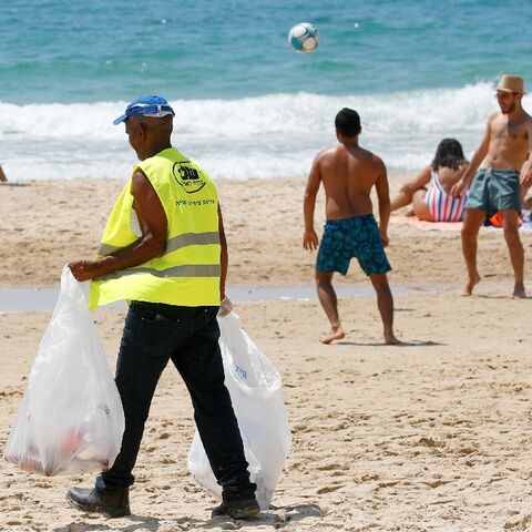 A cleaner collects plastic garbage at a Tel Aviv beach