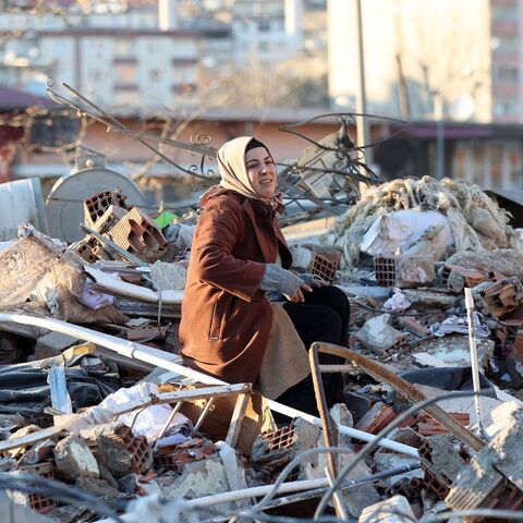 A woman sits on the rubble of a destroyed building in Kahramanmaras, southern Turkey, a day after a 7.8-magnitude earthquake struck the country's southeast, on Feb. 7, 2023.  