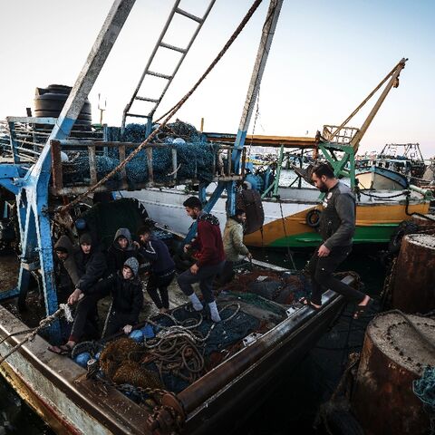 Palestinian fisherman Jihad al-Hissi and his sons aboard their boat at the seaport in Gaza City 