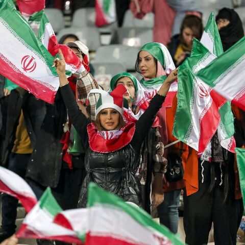 Women football fans wave Iranian flags during the friendly match between Iran and Russia at Azadi Stadium in Tehran