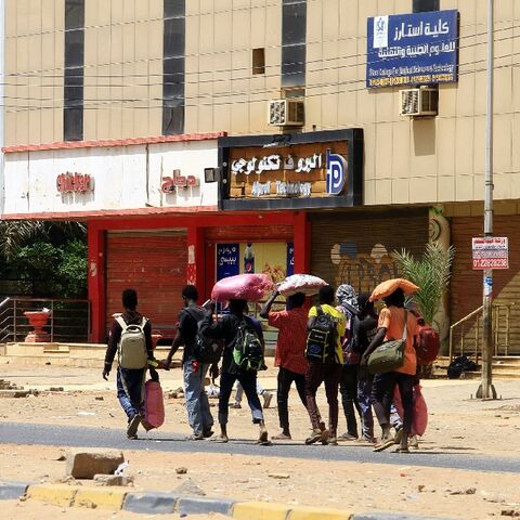 People carry their belongings in Khartoum on Sunday as fighting continues between rival forces