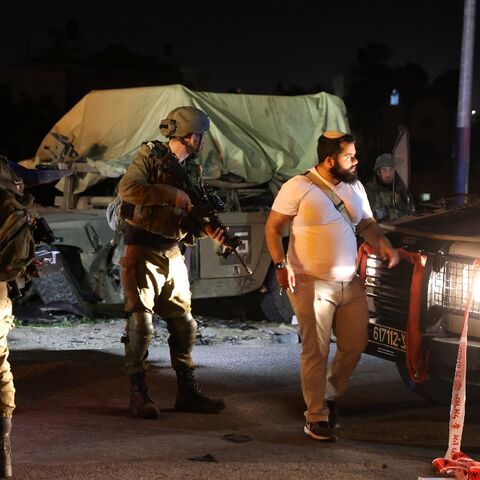 Israeli soldiers stand round a damaged military vehicle at the site of a car ramming attack near the town of Beit Ummar in the occupied West Bank