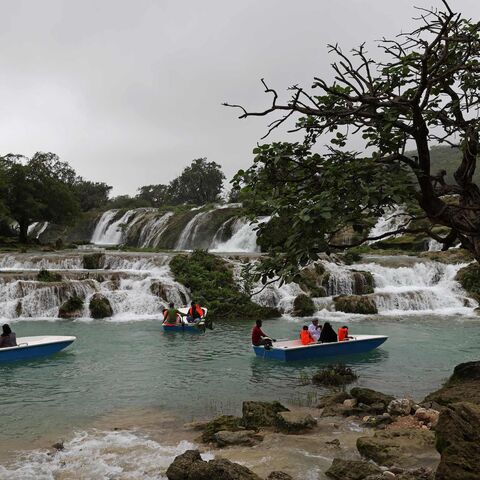 Locals and tourists ride in speed boats at the Wadi Darbat (Darbat Valley) near Salalah, in the southern Omani province of Dhofar on July 21, 2022. (Photo by Mohammed MAHJOUB / AFP) (Photo by MOHAMMED MAHJOUB/AFP via Getty Images)