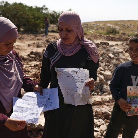 Palestinians pick up papers and books from the site of a school that was demolished by Israeli authorities who said it was built without permission in Jabbet al-Dhib village, east of Bethlehem in the occupied West Bank