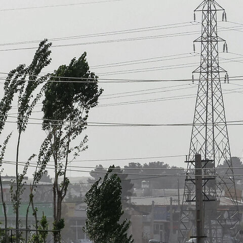 Tree branches flutter near high voltage transmission towers (electricity pylons) during a sandstorm in the south of the capital Tehran on July 4, 2022. (Photo by ATTA KENARE / AFP) (Photo by ATTA KENARE/AFP via Getty Images)