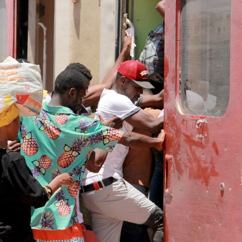 Migrants board a train as they flee amid unrest in the Tunisian city of Sfax
